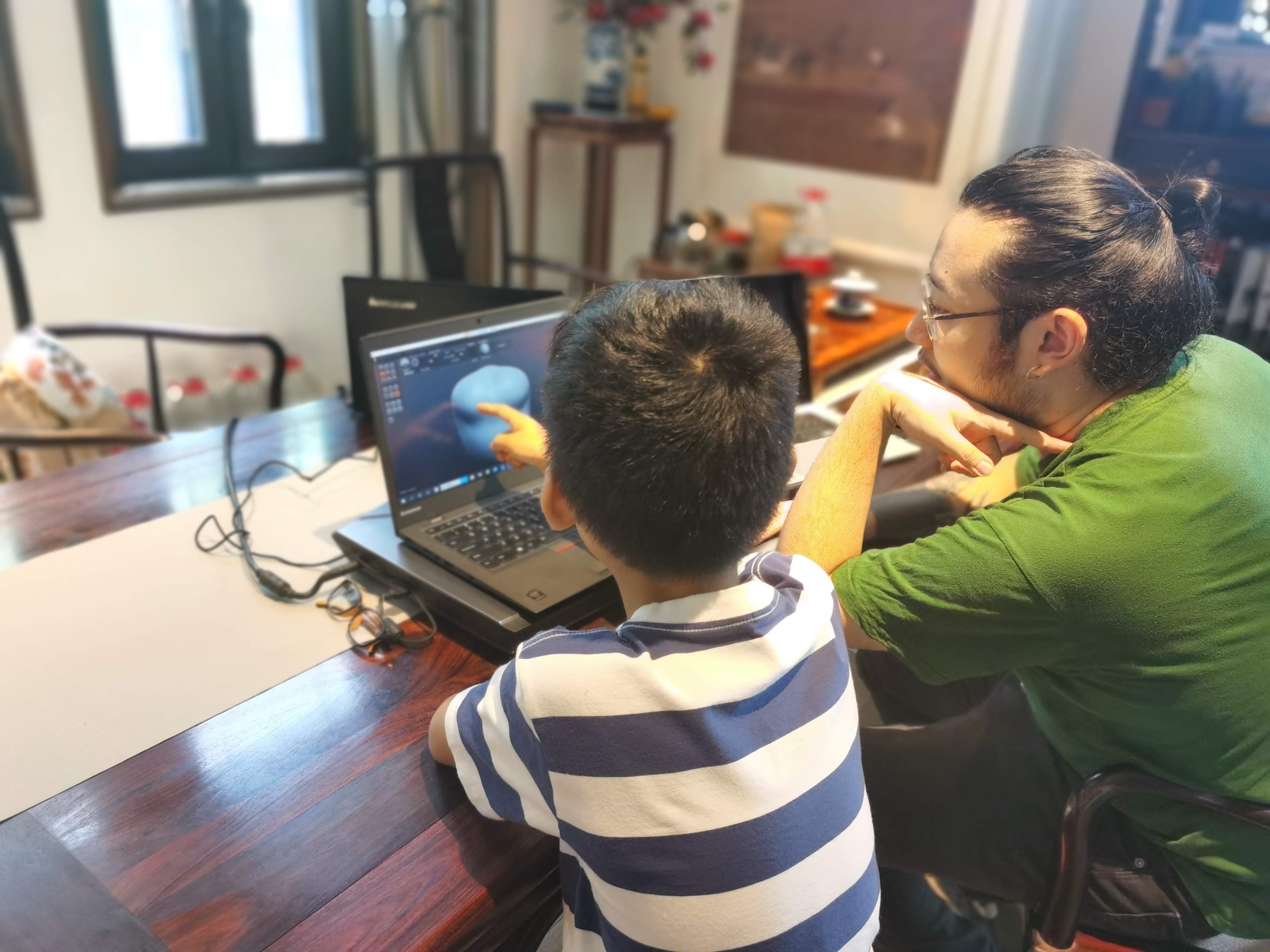 Artist and child collaborator reviewing a three-dimensional model on a laptop